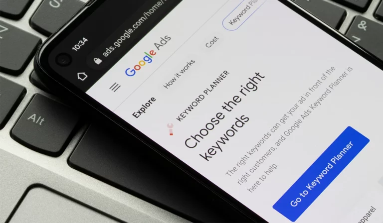 Smartphone mit Google Ads-Website auf dem Bildschirm liegt auf einer Laptop-Tastatur und wird zur Keywordrecherche genutzt. Suchmaschinenoptimierung, Keyword-Recherche, Online-Marketing.